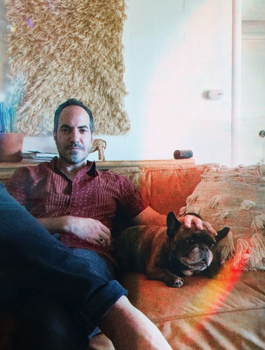 SOHEILL on a couch with his French bulldog, light leak across the frame.